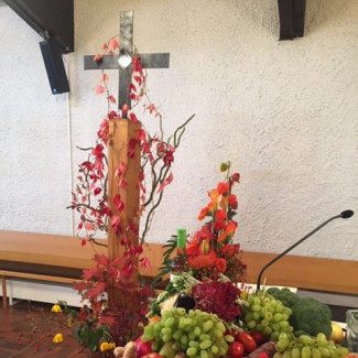 Bild von einem geschmückten Kreuz, Erntedankgaben sichtbar